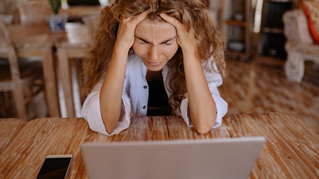 Woman with hands on head frustrated with technology